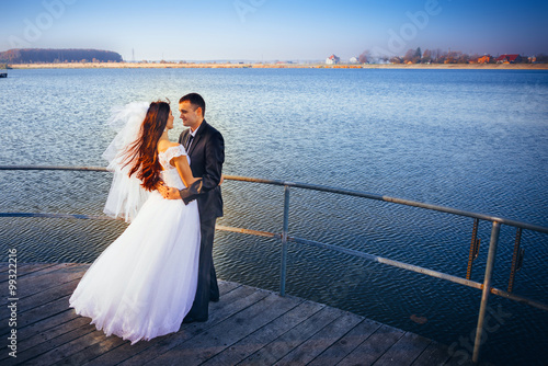 Beautiful bride embrace stand on bridge near the lake © masik0553