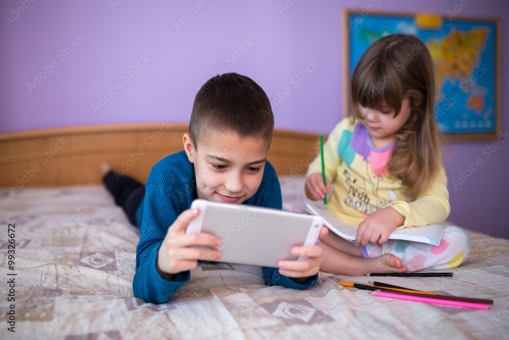 Brother and Sister Having Fun with tablet at home / brother and sister using a digital tablet while lying on the bed at home
Brother and Sister Having Fun with tablet at home / brother and sister using a digital tablet while lying on the bed at home