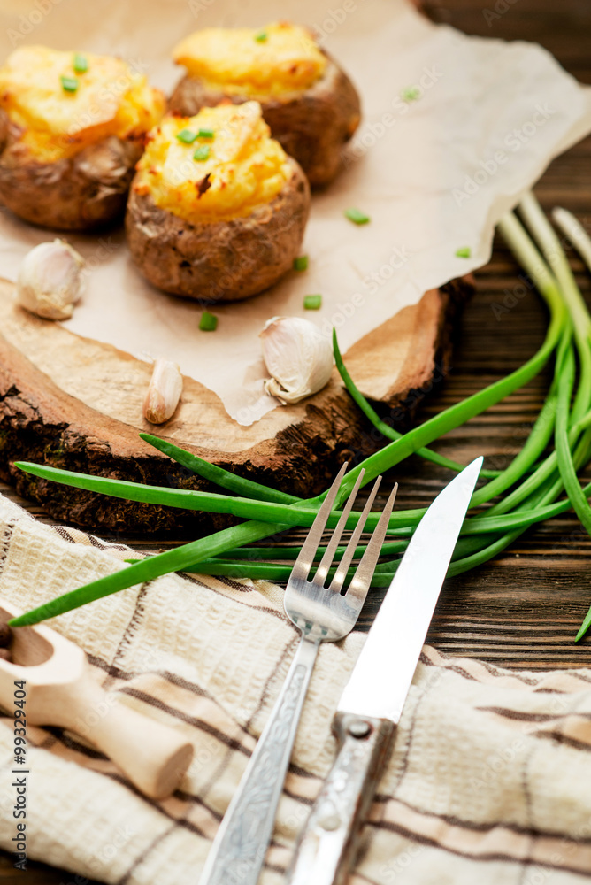 hearty and healthy dinner , baked potatoes in their skins with cheese , herbs , spices and garlic on a wooden background
hearty and healthy dinner , baked potatoes in their skins with cheese , herbs , spices and garlic on a wooden background