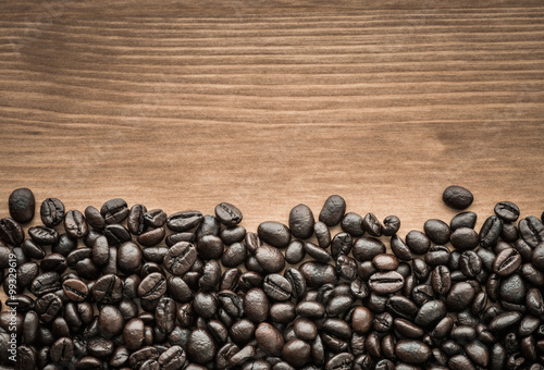 background of brown coffee beans on wood board © wuttichok
