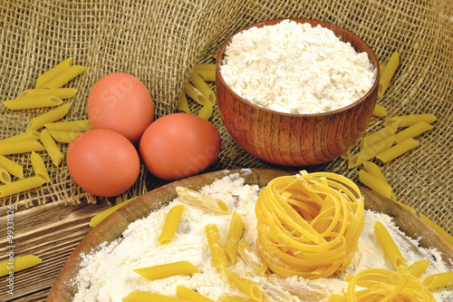 Photo pasta flour and eggs lie on a wooden table for cooking
