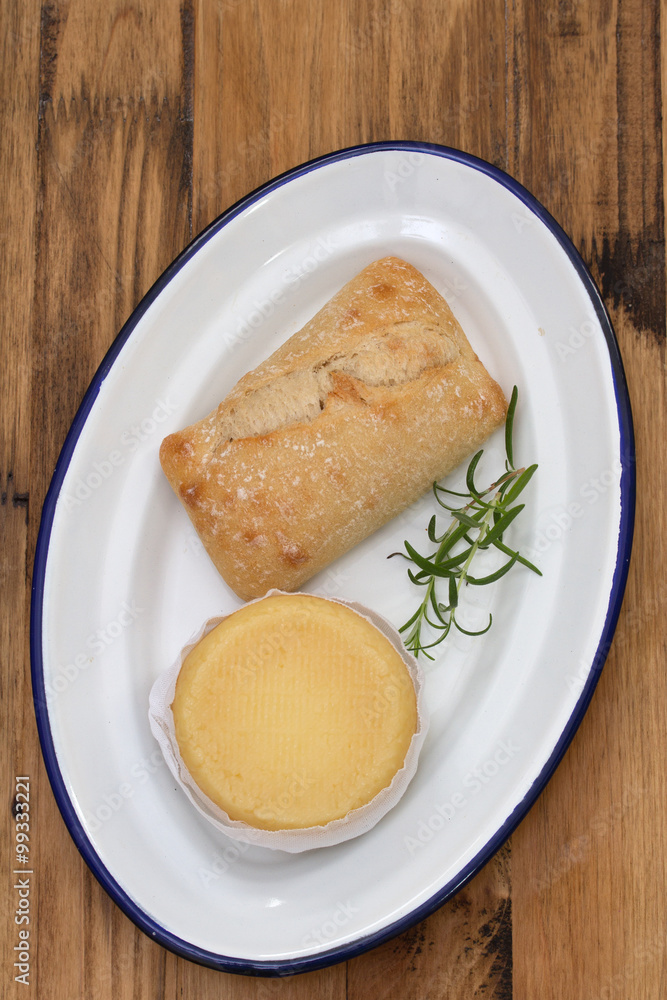 cheese with bread on white dish on brown wooden background