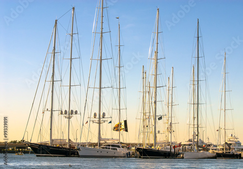 Sun sets behind tall sailing vessels in Newport, Rhode Island. Newport Harbor invites these unique sailing vessels from all over the world.