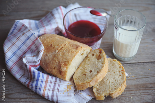 Freshly baked bread served with jam and glass of milk.