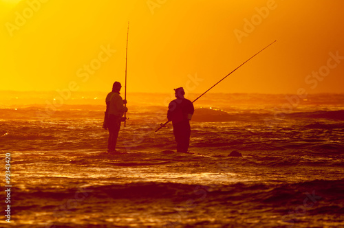 Silhouette of two anglers against sunset