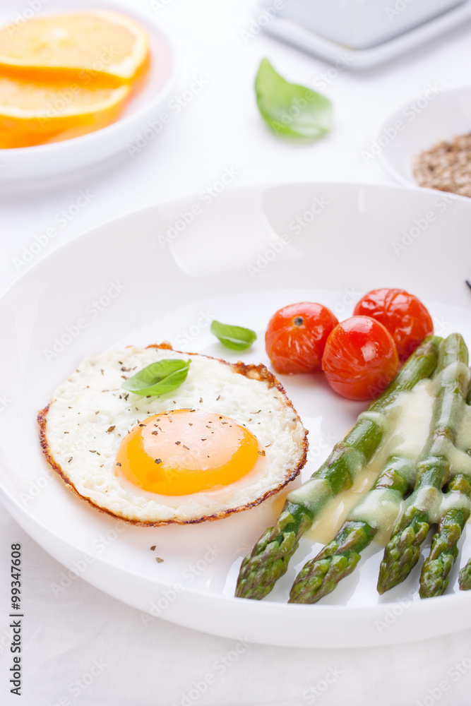 Fried egg with asparagus and tomatoes on a white plate with blue napkin. .. Fried egg with asparagus and tomatoes on a white plate with blue napkin. ..