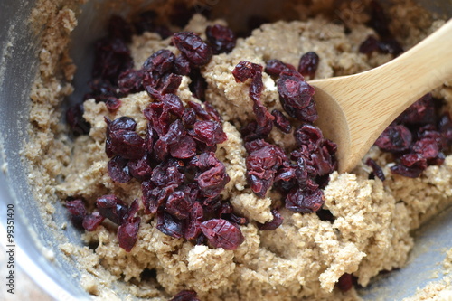 Homemade oatmeal cookie dough with dried cranberry raisins in mixing bowl with wooden spoon