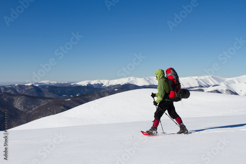 Winter hiking in the mountains on snowshoes with a backpack and tent.