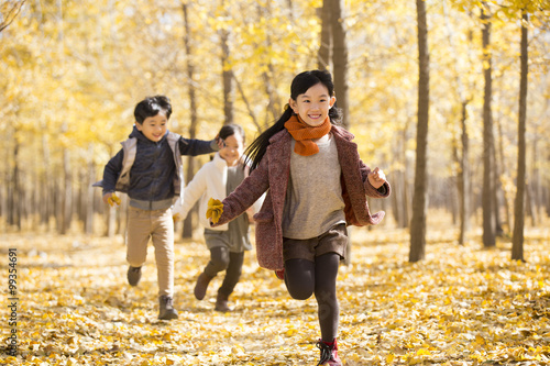 Three children running in autumn woods