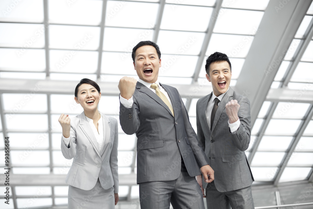 Excited business people celebrating in airport lobby Excited business people celebrating in airport lobby