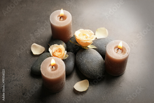 Relax concept - composition of aroma candles with pebbles and flower on grey background