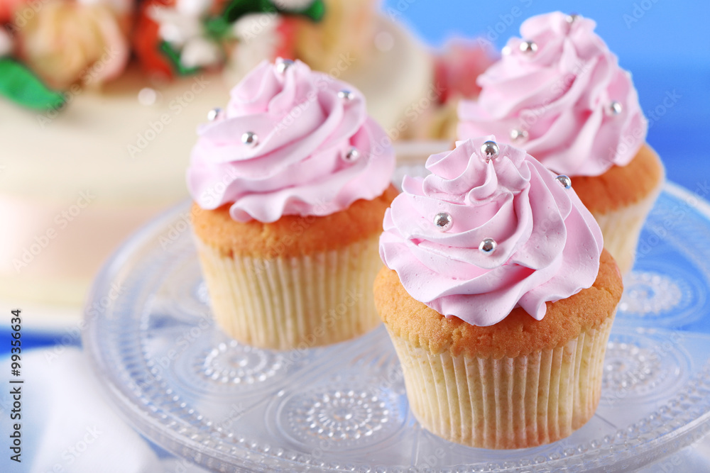 Tasty cupcakes on stand and cake, on table, on color background