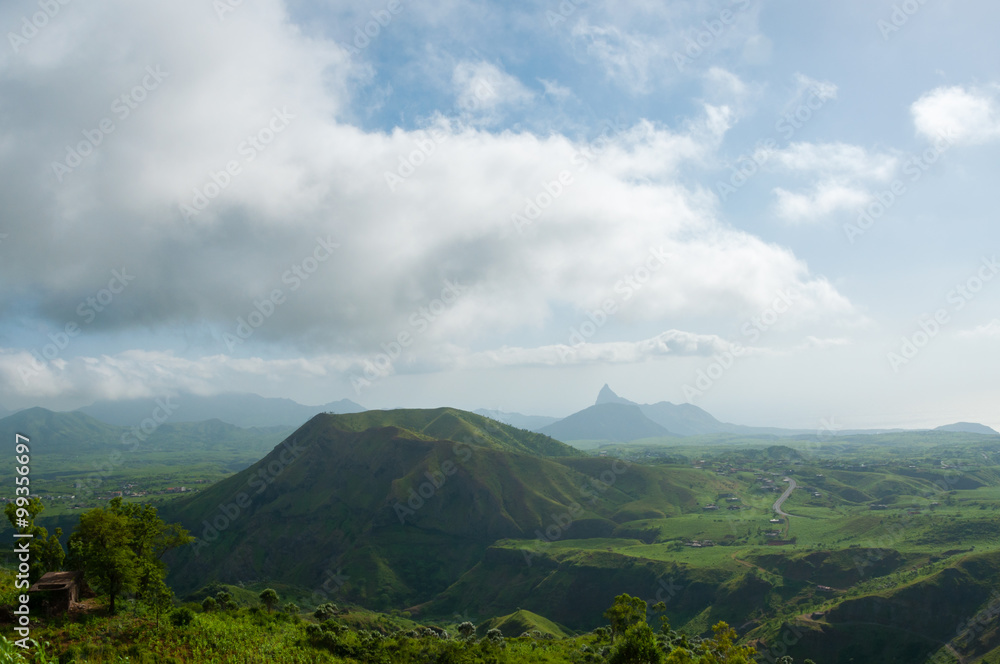 Green valley with hill in the middle under cloudy sky