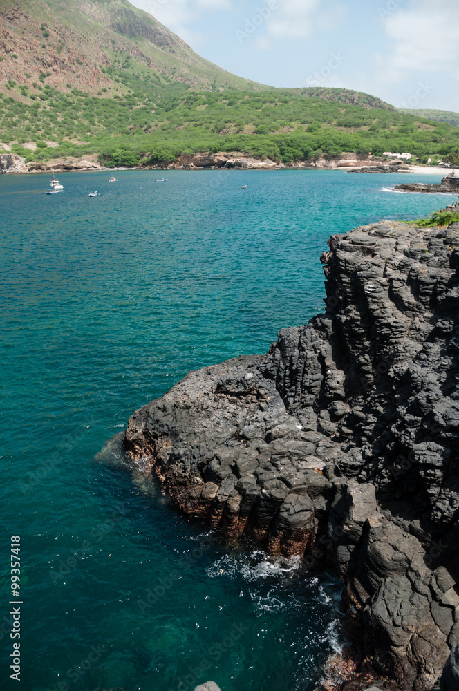 Dark black rock cliff and blue ocean coast