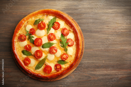 Pizza Margherita with arugula on wooden background
