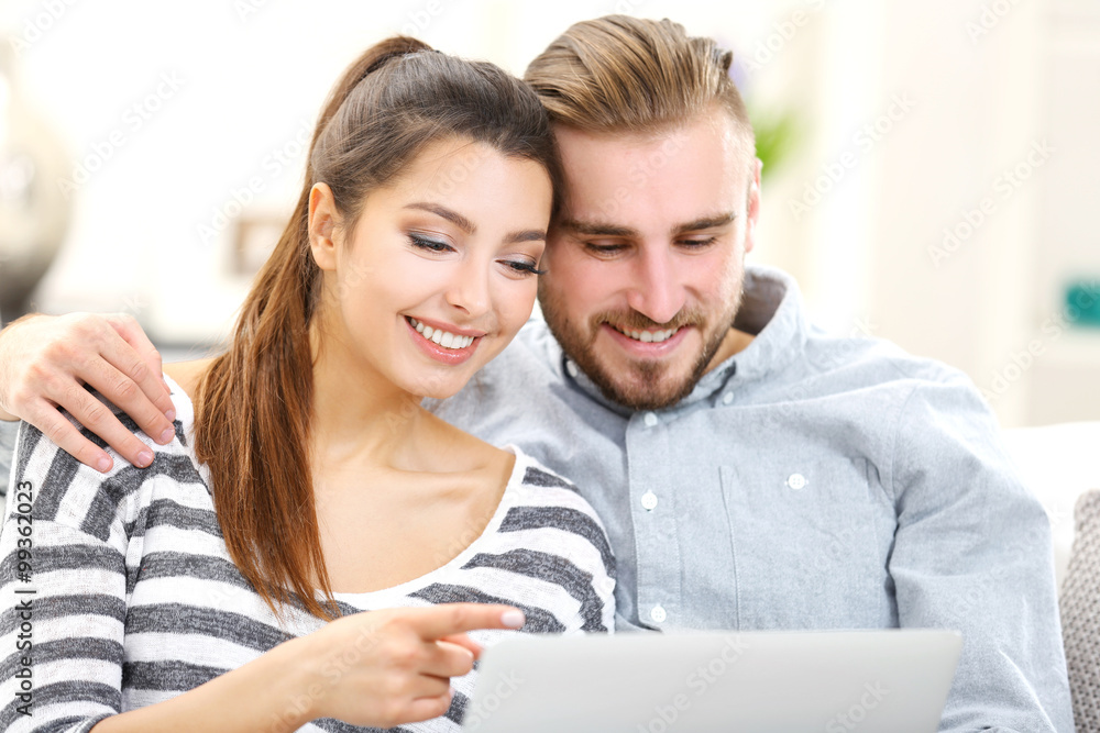 Happy couple sitting on sofa and working on a laptop Happy couple sitting on sofa and working on a laptop