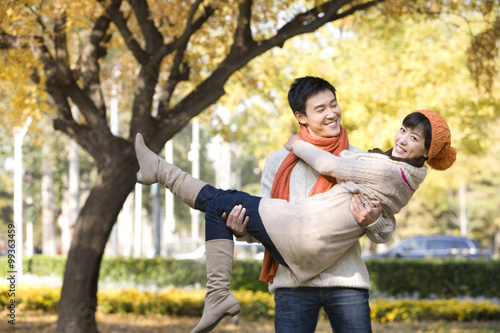 Young Man Carrying a Young Woman in a Park