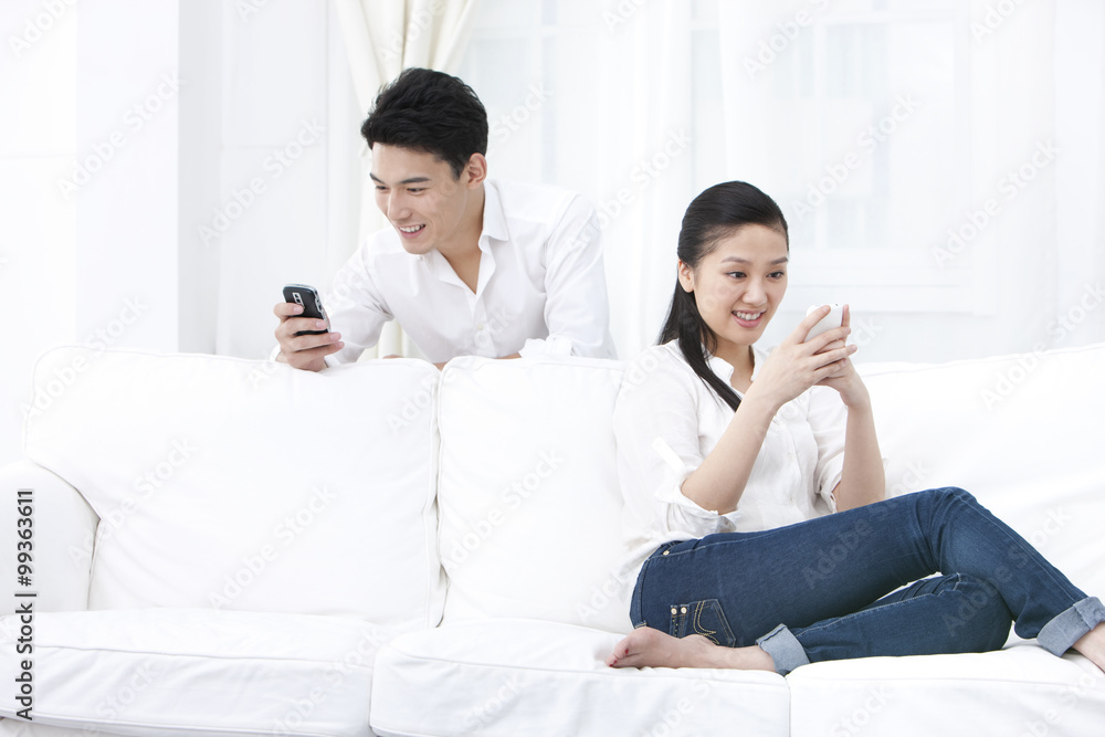 Couple using phones together at home Couple using phones together at home