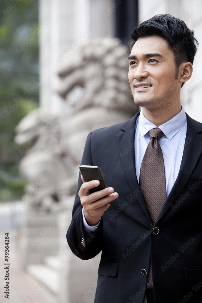 Confident businessman with smart phone looking at view, Hong Kong Confident businessman with smart phone looking at view, Hong Kong