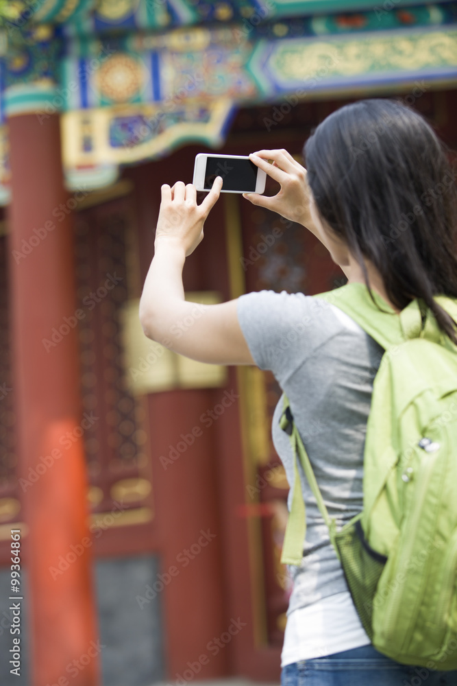 Young woman taking pictures with smart phone in the Lama Temple