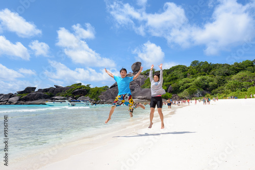 Tourist couple jumping for happy on beach near the sea under the blue sky and cloud of summer at Koh Similan Island in Mu Ko Similan National Park, Phang Nga province, Thailand