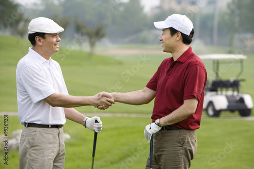 Two golfers shaking hands on the course