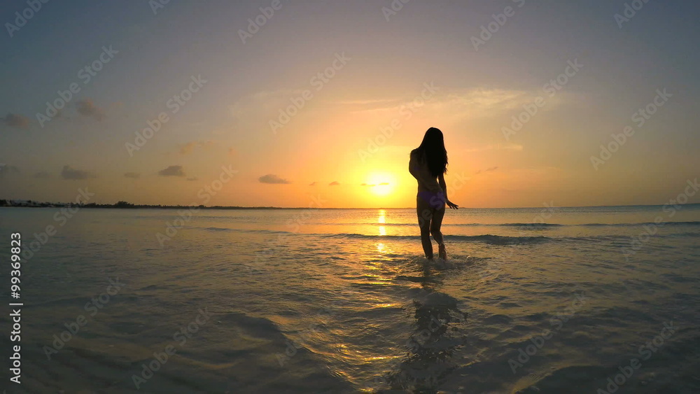 Young ethnic female in bikini dancing on the beach at sunset Young ethnic female in bikini dancing on the beach at sunset