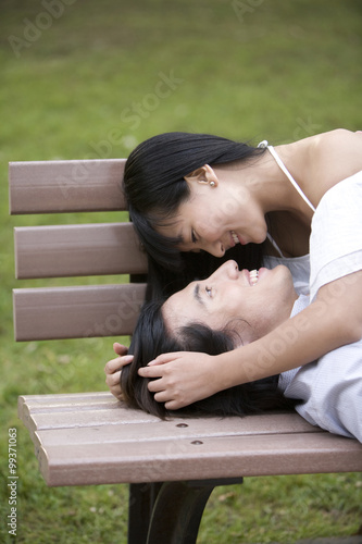 Young couple lying on bench, outdoors © Blue Jean Images
