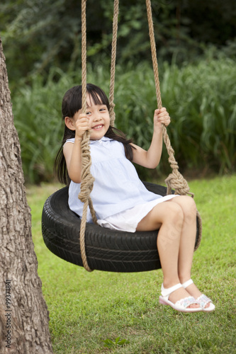 Cheerful little girl playing on a swing © Blue Jean Images