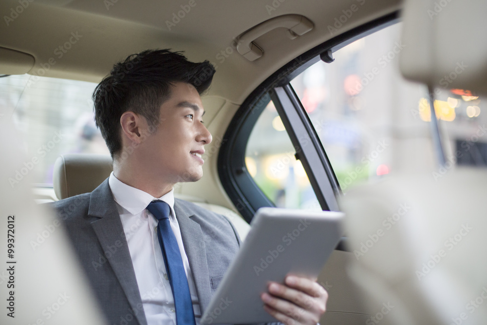 Businessman holding digital tablet while traveling by car Businessman holding digital tablet while traveling by car