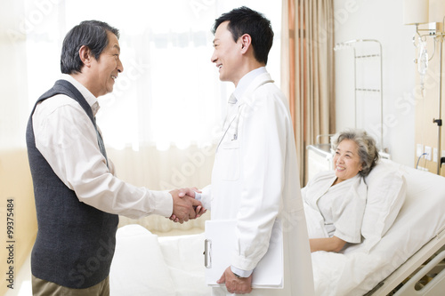 Senior couple shaking hands with doctor in hospital