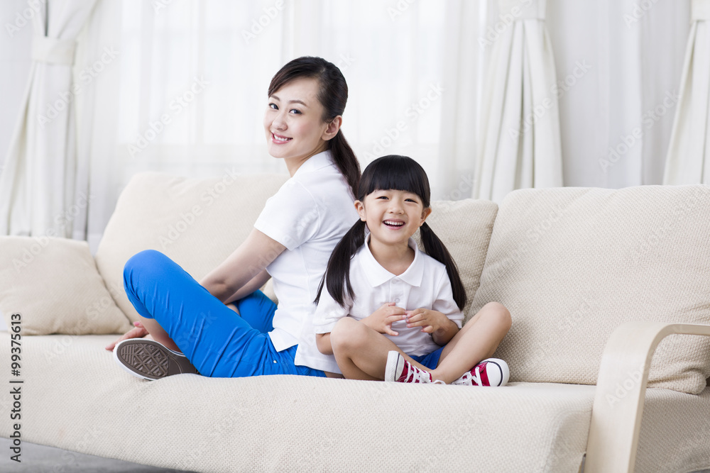 Mother and daughter sitting back to back