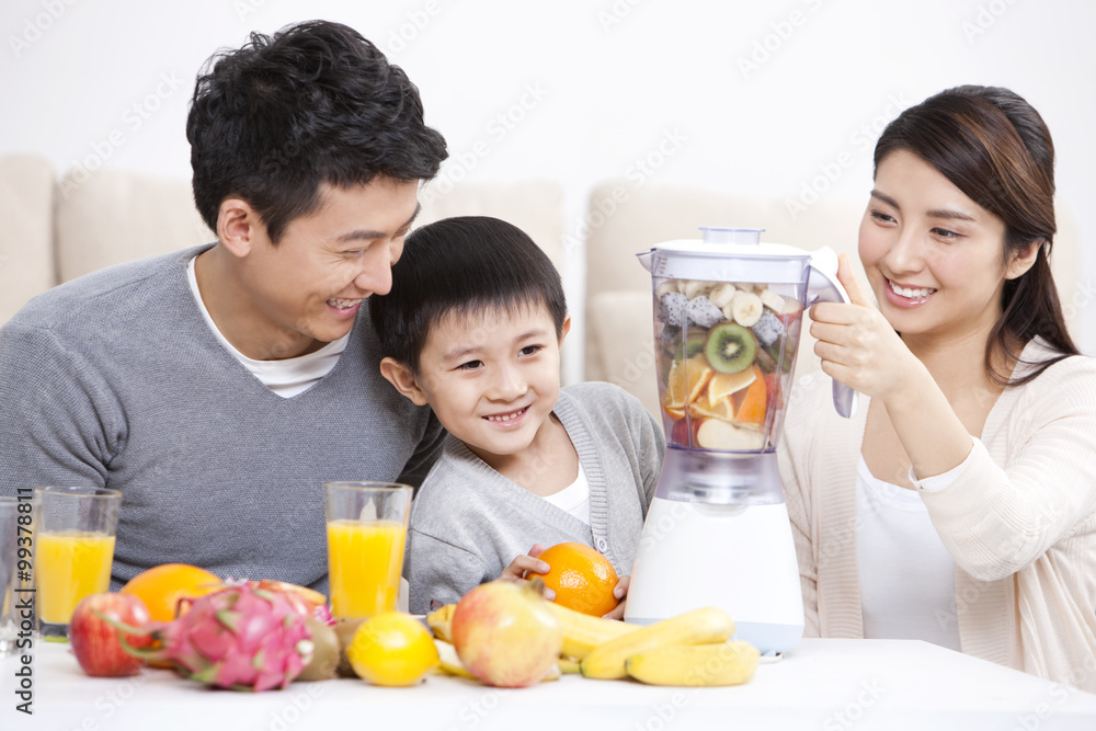 Happy family making juice with electric juicer