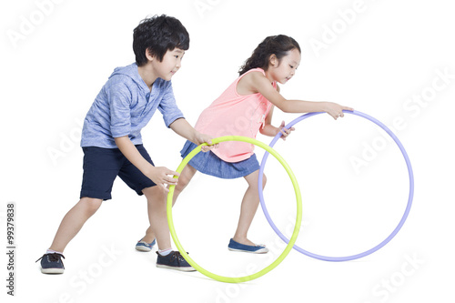 Happy children rolling plastic hoops