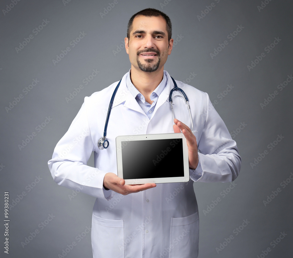 Portrait of a doctor with tablet in hands on grey background Portrait of a doctor with tablet in hands on grey background