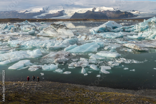 Ice cube and iceberg at Jokulsarlon glacial lagoon with snow mountain background with group of tourist
