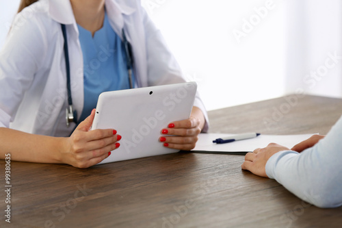 Doctor holding tablet while talking with patient