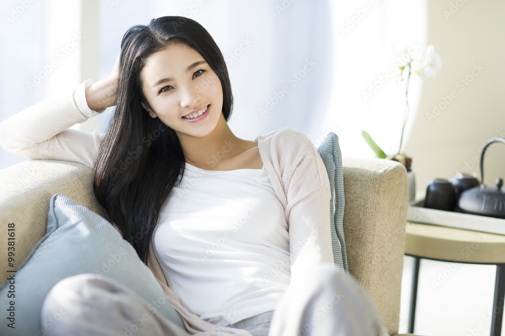 Happy young woman sitting on sofa Happy young woman sitting on sofa