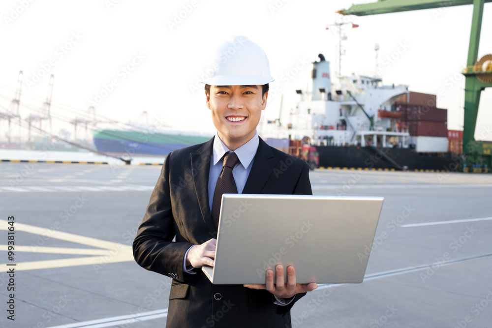 businessman using a laptop at a shipping port businessman using a laptop at a shipping port