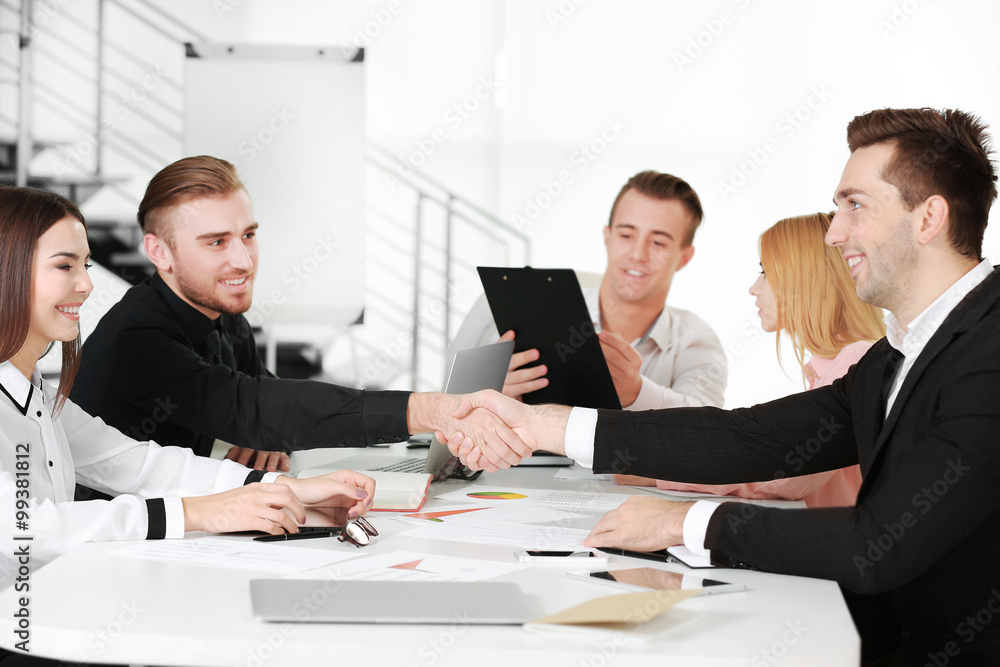 Two young business men shaking hands at the meeting in a conference room Two young business men shaking hands at the meeting in a conference room