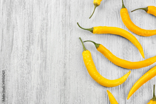 Yellow chili peppers on light wooden background
