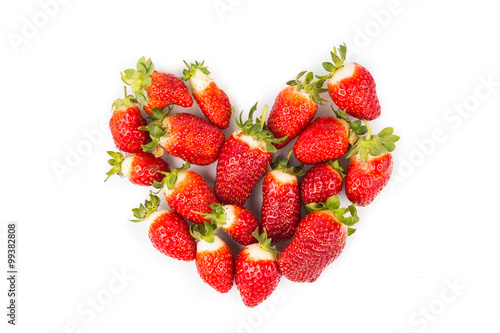 Heaps of strawberries form heart shape on white background