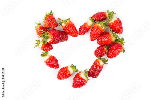 Heaps of strawberries form heart shape on white background