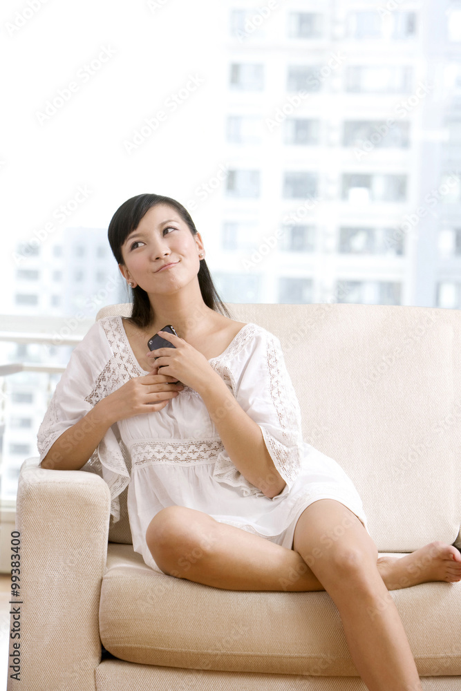 Asian woman playing with cell phone on a sofa