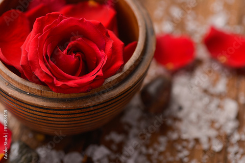 Roses in bowl with pile of salt  stones on old wooden board