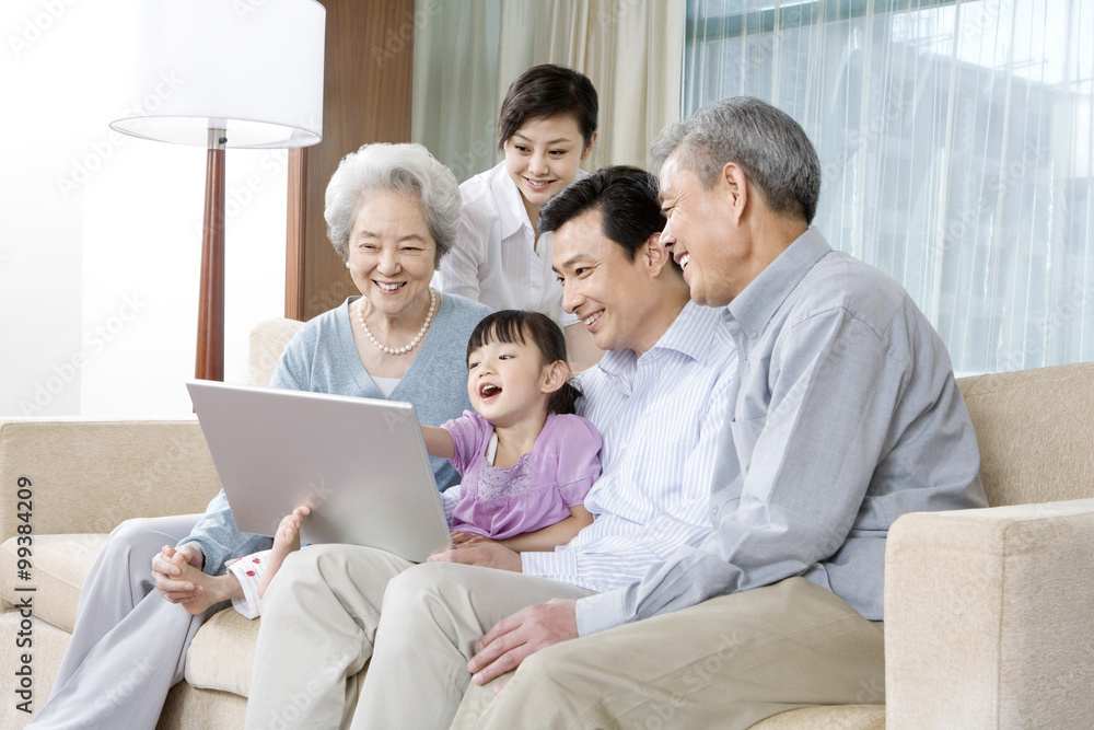 Grandparents and Parents with daughter look at Laptop on a sofa Grandparents and Parents with daughter look at Laptop on a sofa