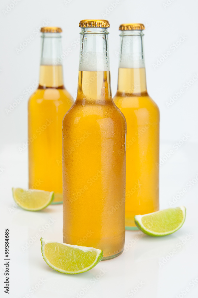 Fototapeta premium Cerveza Beer Bottles With Limes On White Background Closeup