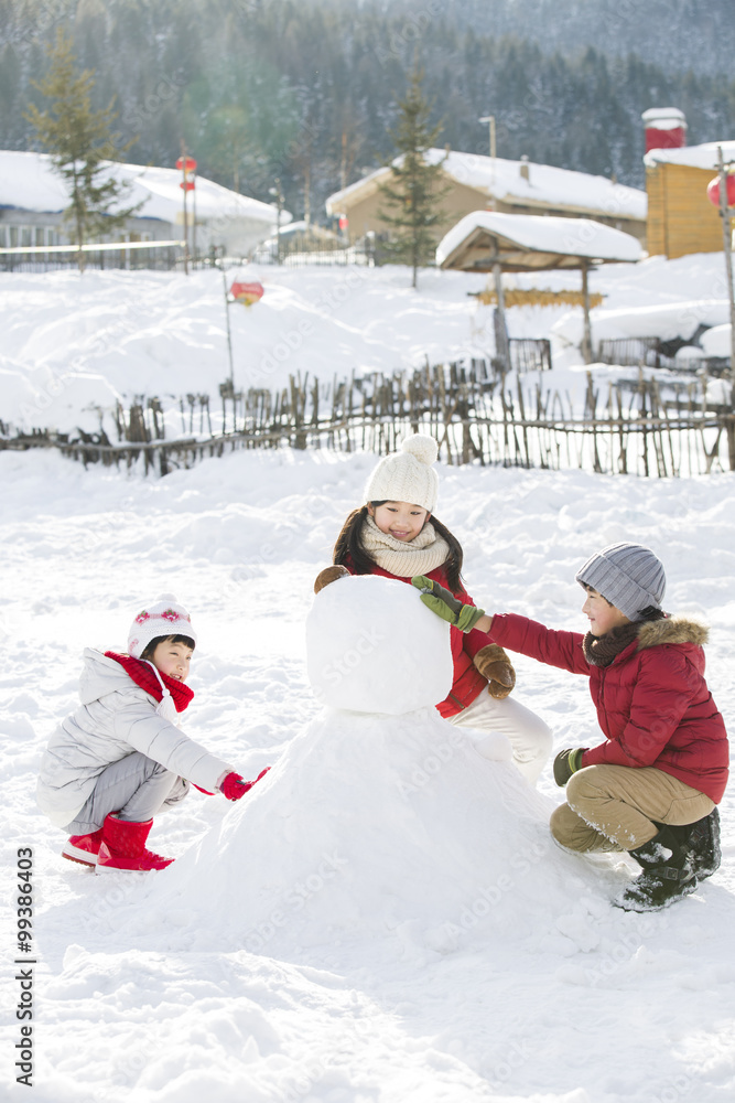 Happy children making snowman together