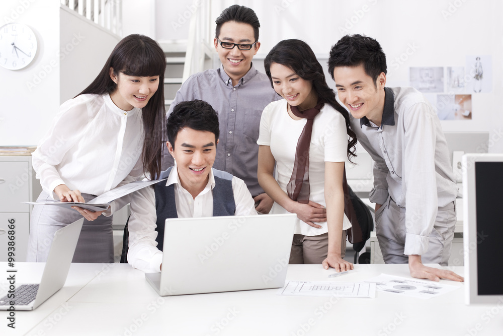 Happy office workers looking at laptop Happy office workers looking at laptop
