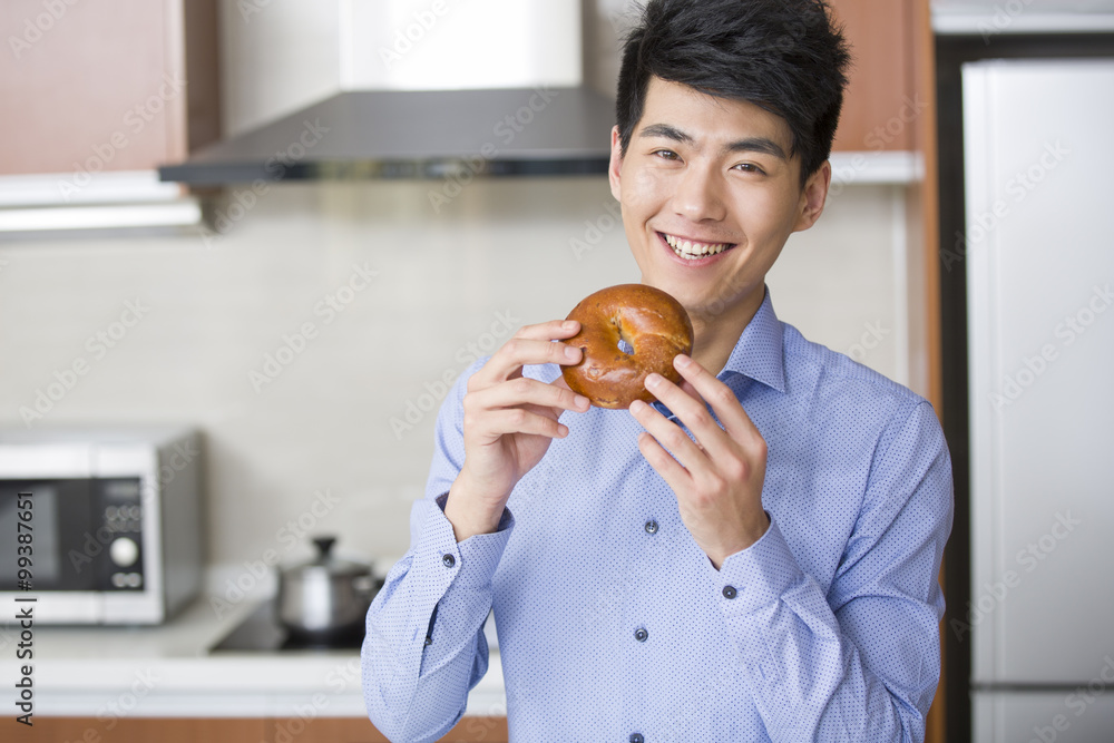 Happy young man eating bread in the kitchen Happy young man eating bread in the kitchen